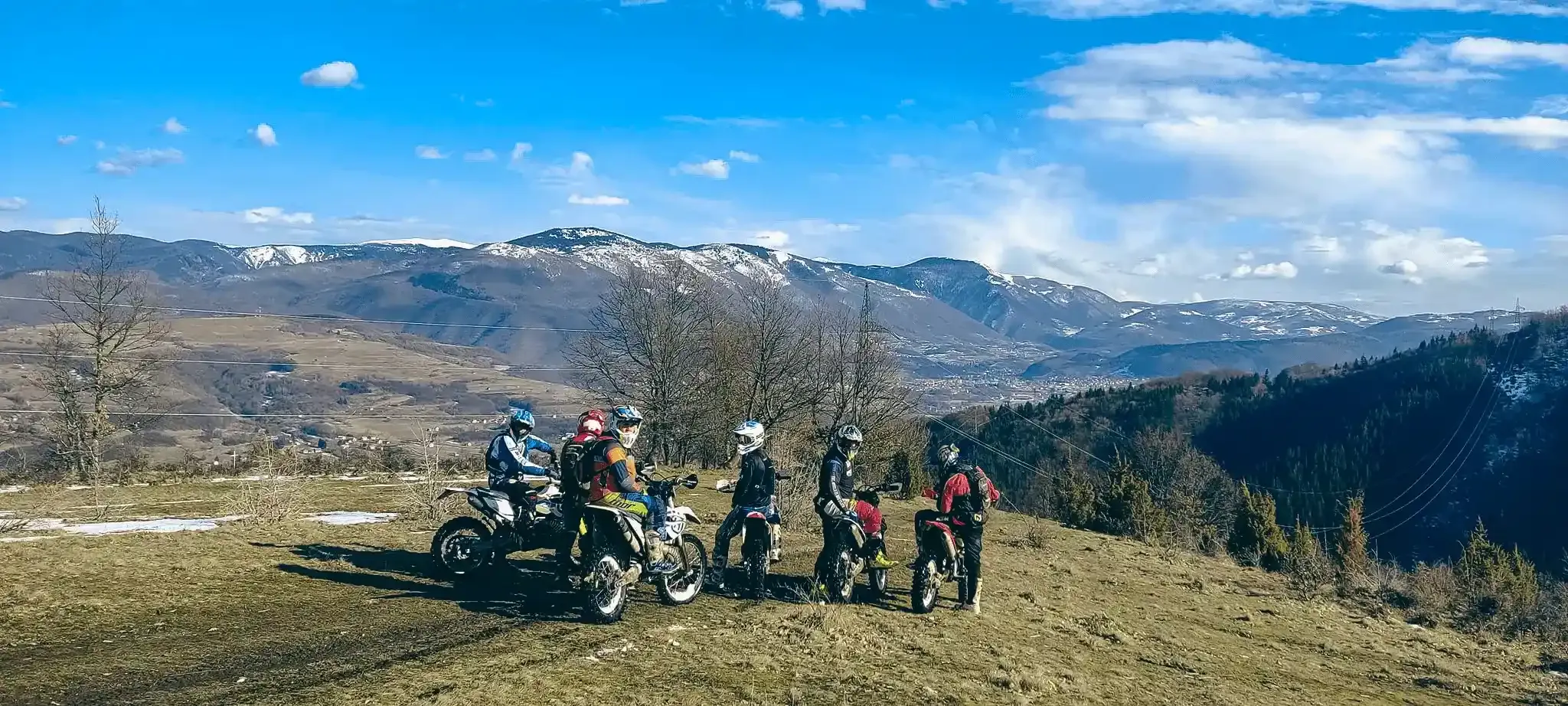 Enduro-Gruppe mit Motorrädern auf einer Bergwiese mit Blick auf die Berge Bosniens