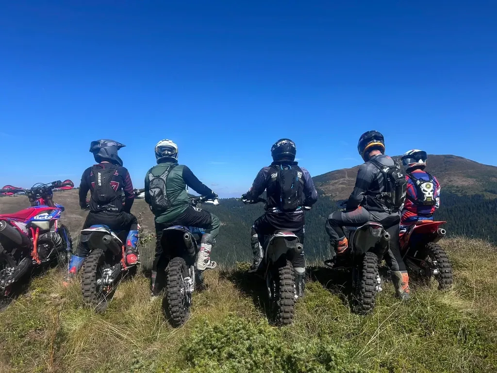 Enduro-Fahrer stehen mit ihren Motorrädern am Berghang und genießen die Aussicht