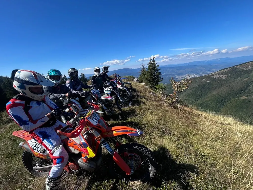 Enduro-Fahrer in Rennausrüstung auf einem orangen Motorrad auf einem Bergpfad