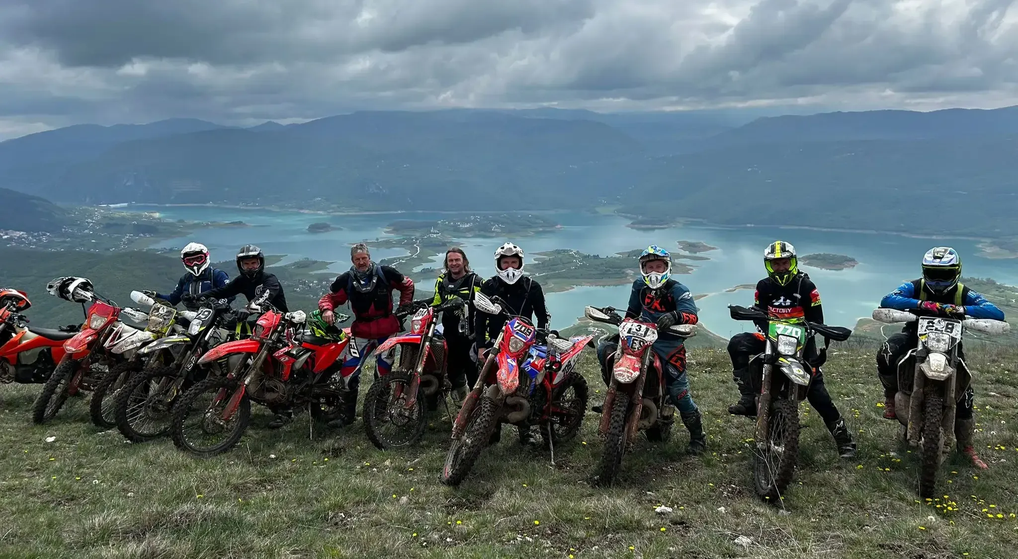 Enduro-Gruppe mit ihren Motorrädern hoch über einem See in den Bergen