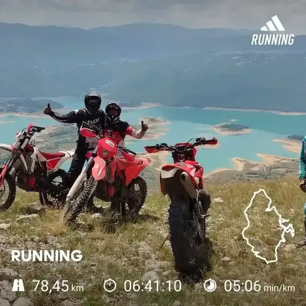 Enduro-Fahrer mit ihren Motorrädern über einem türkisfarbenen Bergsee